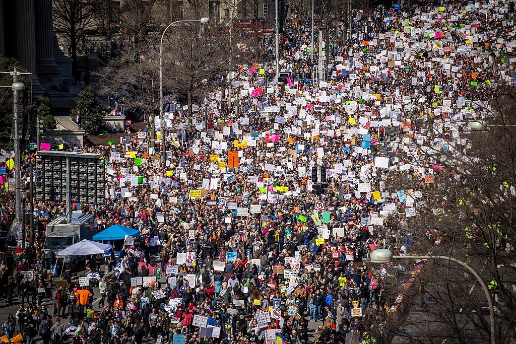Aerial view of large crowd with signs marching in streets during march for our lives protest