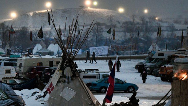 Native American people during a snowy winter with cars and teepee protesting big oil at Standing Rock against Dakota Access Pipeline in 2016
