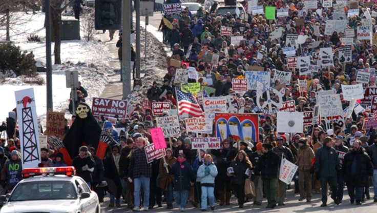Crowd of people with protest signs marching in the street against the war in Iraq in 2002 and 2003