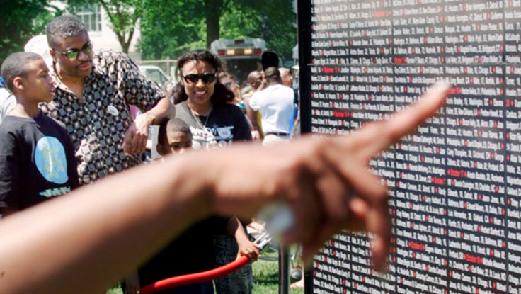 Black family standing in front of wall of names at the Million Mom March for stricter gun control in 2000
